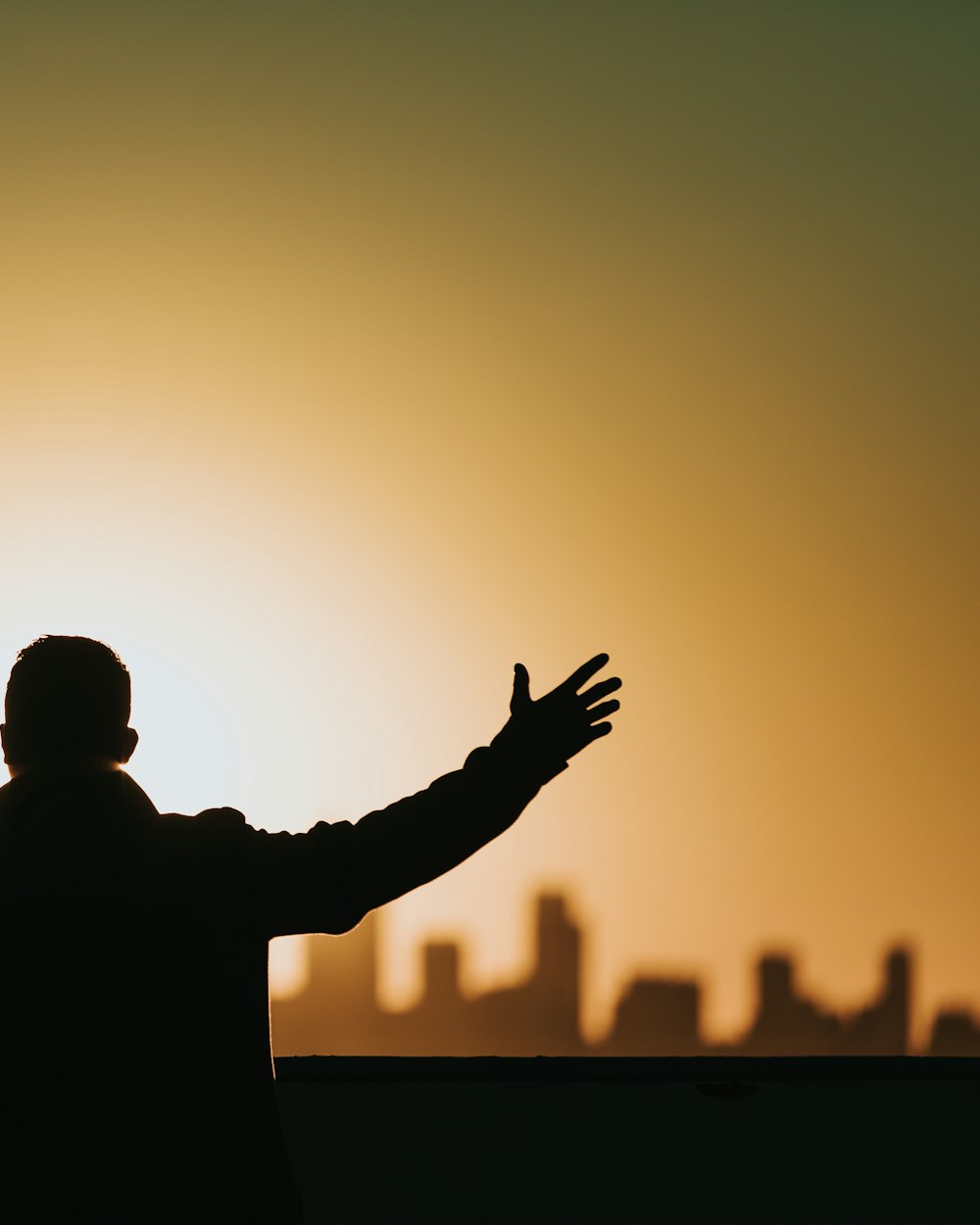 A man with an arm raised in worship against an evening sky